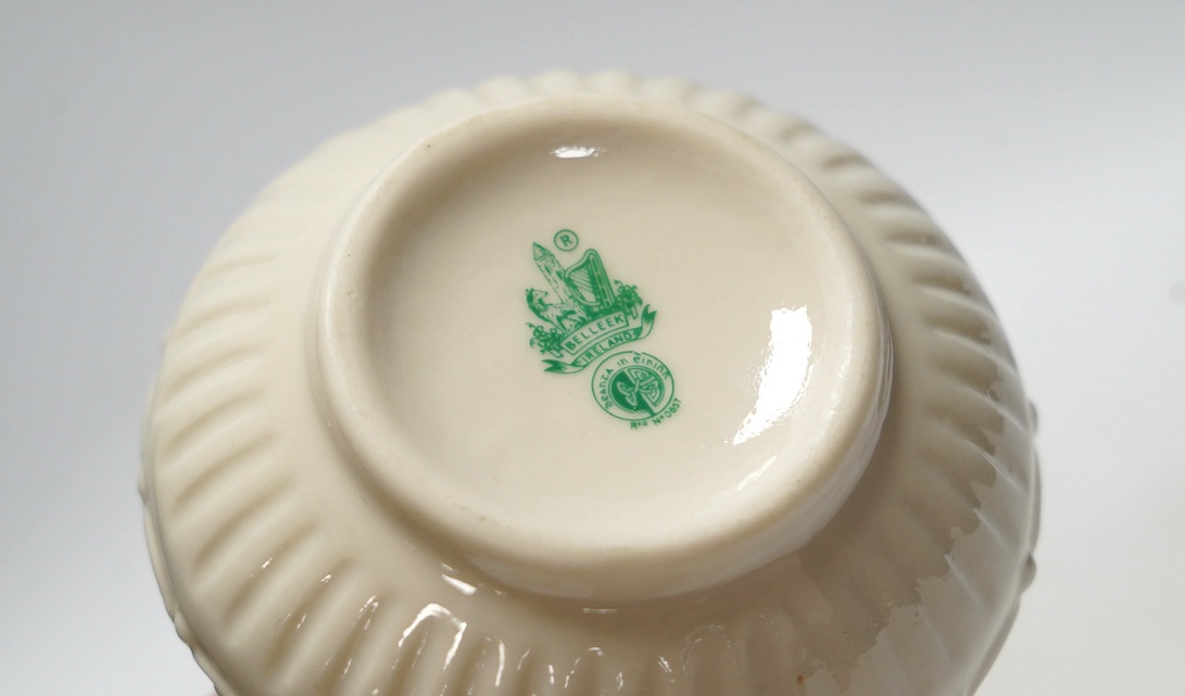 Three 20th century Belleek items with applied floral decorations; a jug, 15cm high, and two basket work dishes, largest 20cm wide. Condition - good